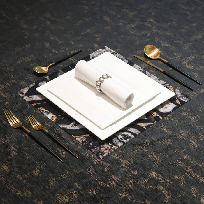 White agate charger plate with natural stone veining, styled with gold flatware and glassware on dark textured surface.