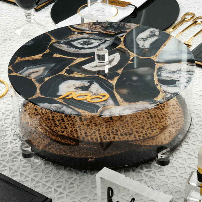 Black agate matzah box with gold veining and lucite base, displayed on formal dining table setting for Pesach.