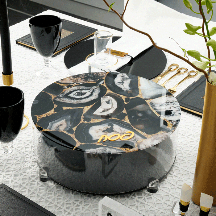 Black agate matzah box with gold veining and lucite lid, displayed on white surface with tabletop styling for Pesach.