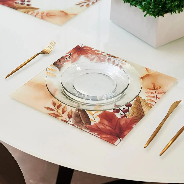 Autumn Chargers by Waterdale Collection featuring warm-toned watercolor leaves in burgundy and gold on white linen, styled with clear glass charger and gold flatware on white round table.