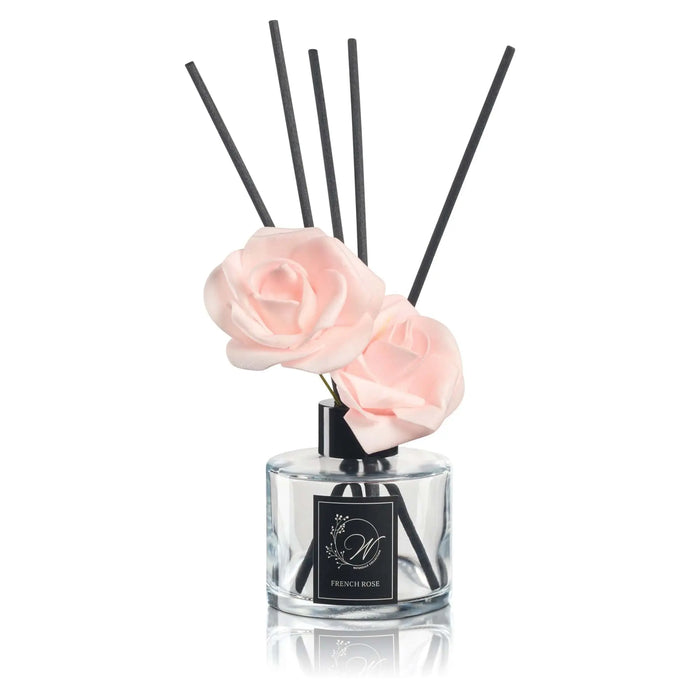 Blush Bloom Diffuser with clear glass bottle and black reed sticks, featuring a white cloud-shaped decorative topper from Waterdale Collection.