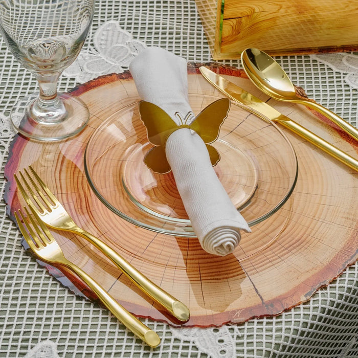 Rose gold butterfly napkin rings displayed on a place setting with champagne glasses and gold flatware on a textured tablecloth.