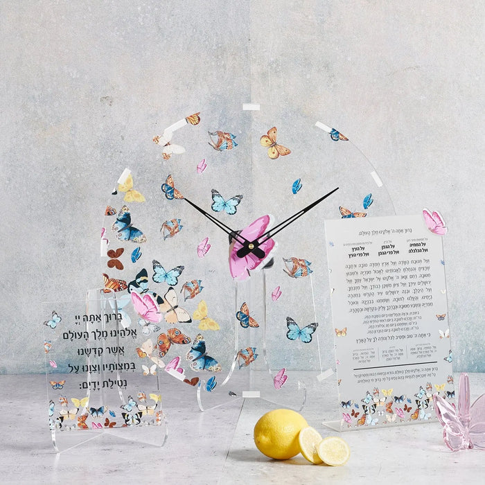 Butterfly tabletop al hamichya plaque with colorful illustrated butterflies, pink flowers, and black clock hands on clear acrylic, displayed with lemon and pink vase.