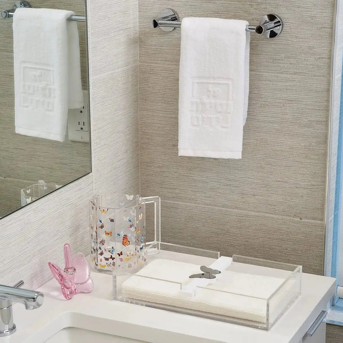 Waterdale Collection butterfly washing cup in cream ceramic displayed on a bathroom vanity counter next to white towels and toiletries.