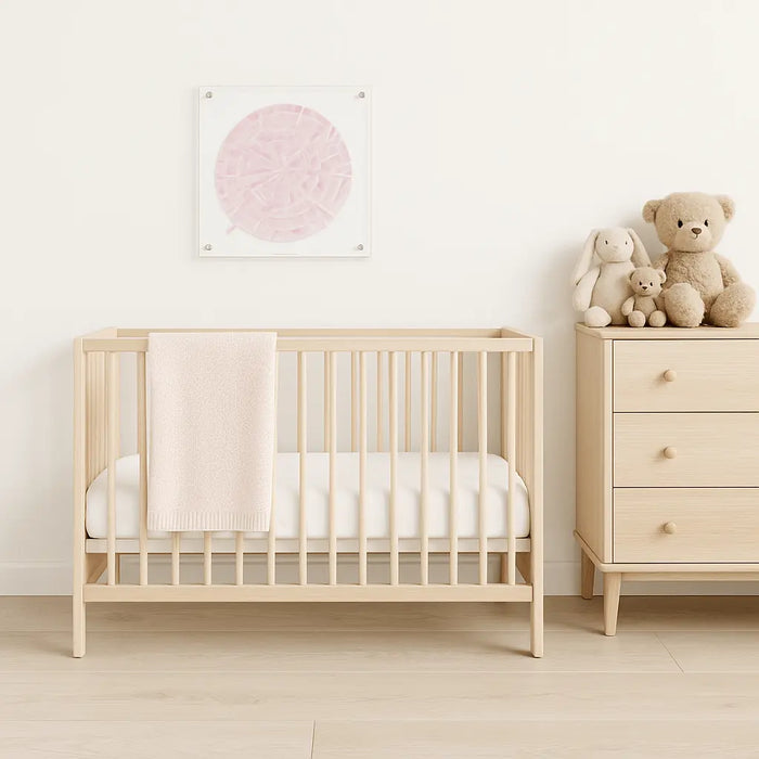 Calligraphy Aleph Bais wall art in soft pink displayed above a wooden crib in a nursery room with stuffed animals and dresser.