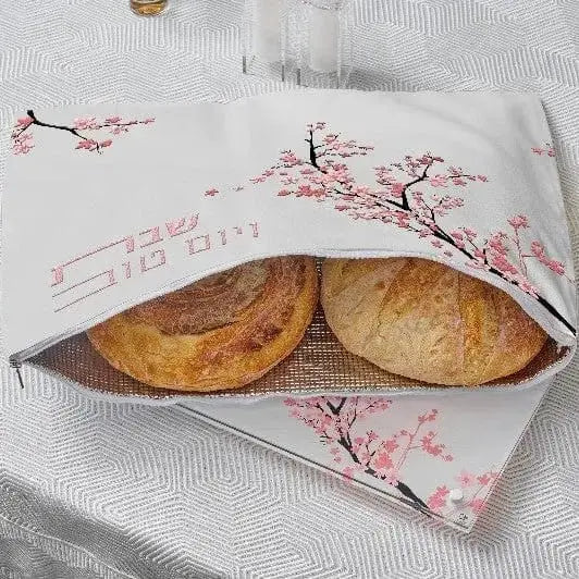 Cherry Blossom Challah Pouch Cover in white with pink floral design, holding two round loaves, leather construction by Waterdale Collection