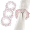 Three Cherry Blossom Napkin Rings in blush pink delicate wirework displayed on white napkins for elegant table settings.