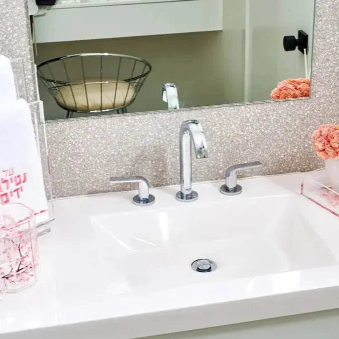 Cherry Blossom Netilas Yadayim Set displayed on white bathroom sink with chrome faucet and mirror backdrop