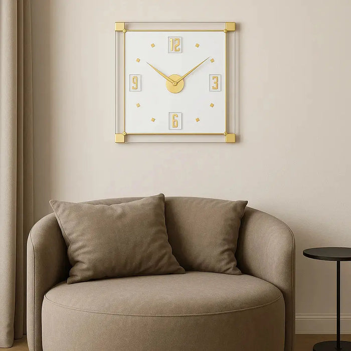 Classic 2.0 wall clock with white face and gold accents displayed above a taupe armchair in a minimalist home setting.