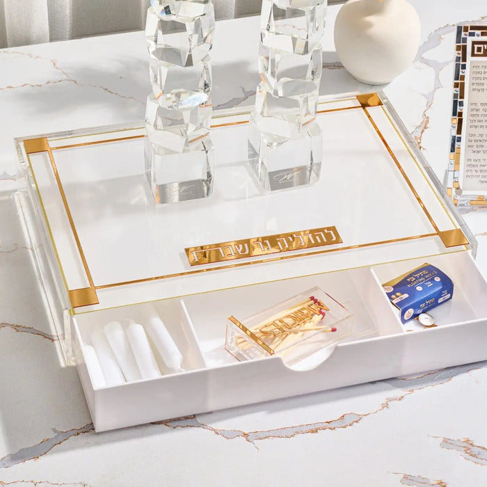 Classic 2.0 Hadlokas Neiros tray in white with gold-tone metal corners, featuring a drawer below and glass candlestick holders on top for Shabbat candle lighting.
