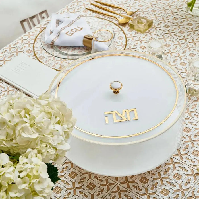 Classic 2.0 Matzah Box in white lucite with gold accents, displayed on a patterned table with flowers and holiday décor