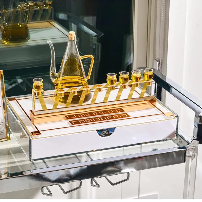The gold Classic 2.0 Menorah Tray styled on a glass cart with an oil jug and gold oil cups, a Waterdale Collection Chanukah set-up
