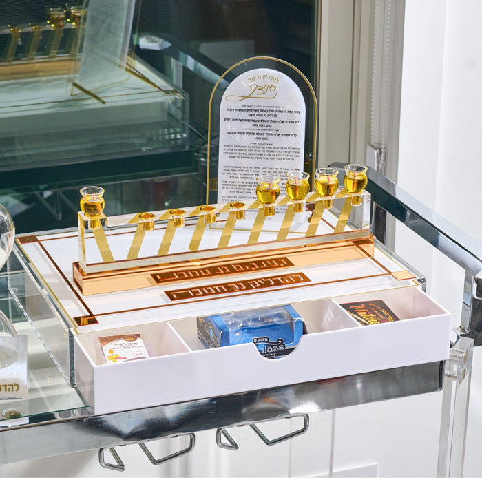 The gold Classic 2.0 Menorah Tray with its drawer open, nine oil cups filled and supplies stored below, set for Hanukkah