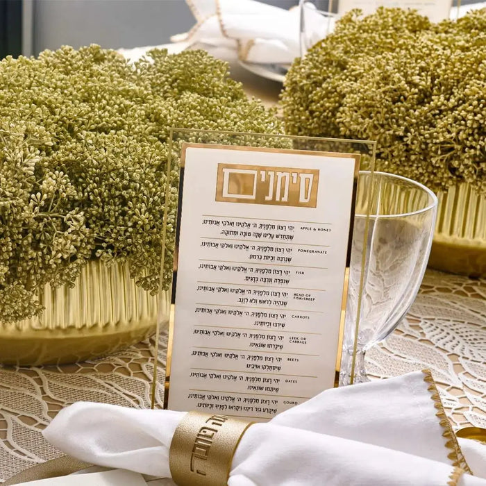 Clear acrylic simanim card with gold accents on a Rosh Hashana table setting