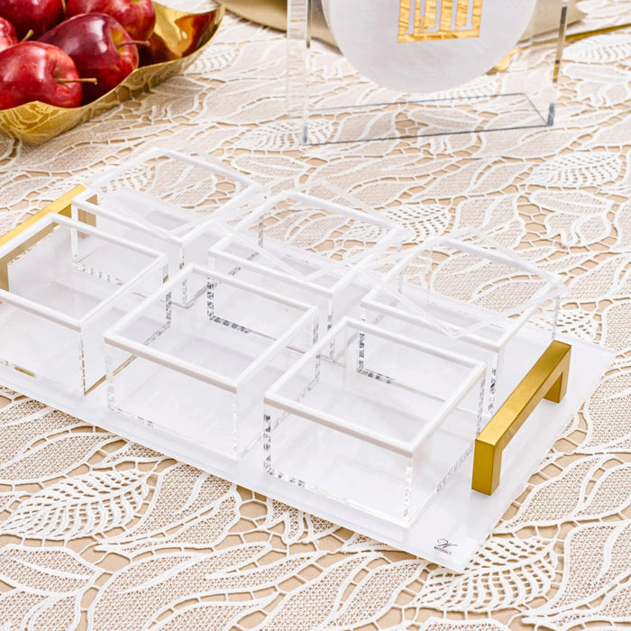 Clear acrylic dip bowl set with gold handles, featuring multiple compartments for serving appetizers and snacks on a marble surface.