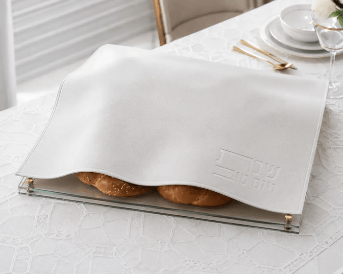 White embossed leather challah cover with gold trim, displayed open to show interior, perfect for Shabbat table settings.