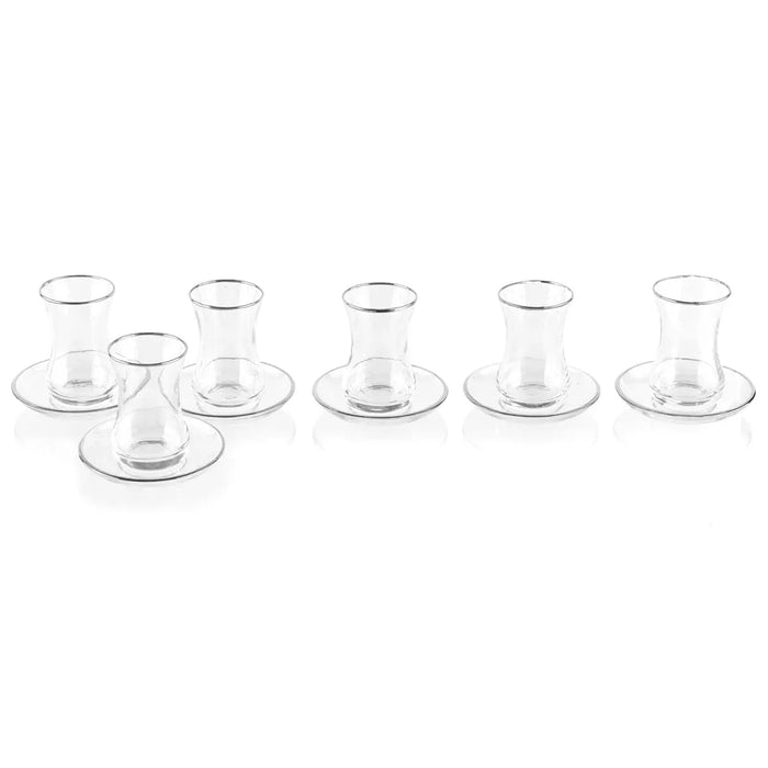 Six clear glass kiddush cups with matching saucers arranged in two rows, classic Pesach tableware from Waterdale Collection.