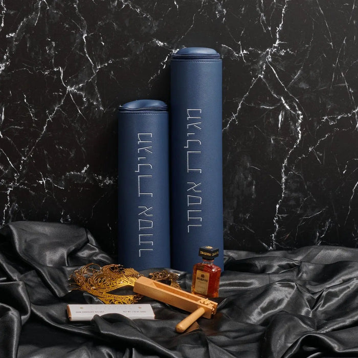 Classic leather megillah case in deep blue with gold-toned hardware, displayed with matching accessories on marble background.