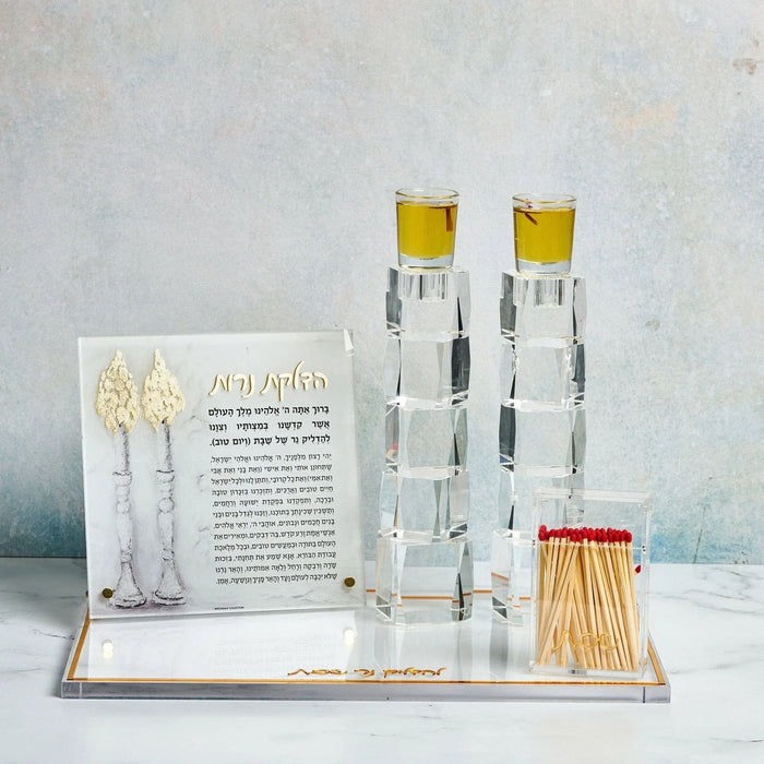 Waterdale Collection Classic Match Holder with clear glass cylinder and brass top, displayed with matches and Jewish holiday candle-lighting items on white shelf.