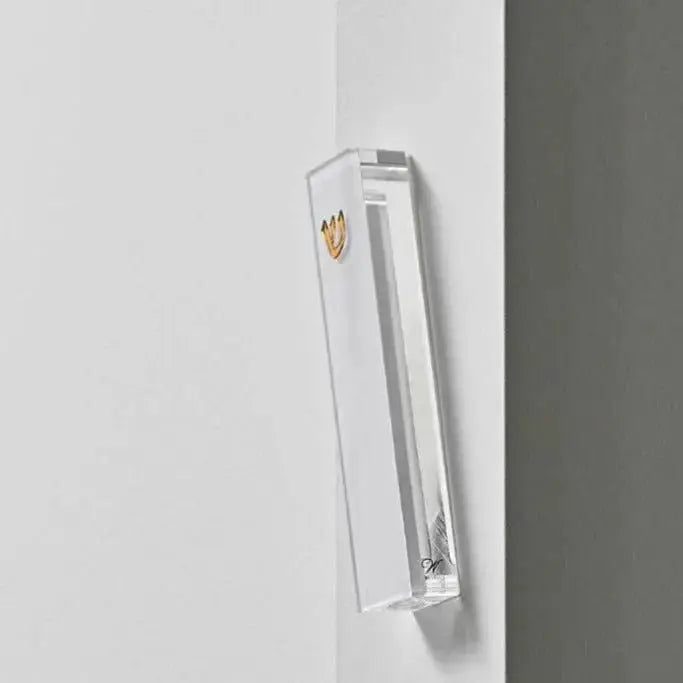 Classic silver mezuzah case mounted on white wall, featuring minimalist rectangular design with hanging cord and small decorative element.