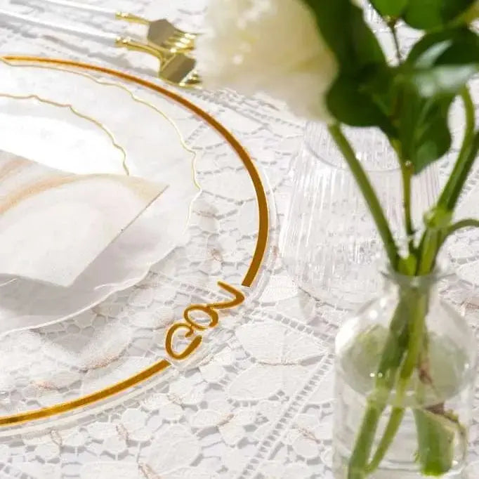 Classic Pesach Charger plate in clear lucite with gold trim, displayed on white linens with fresh greenery and place setting.
