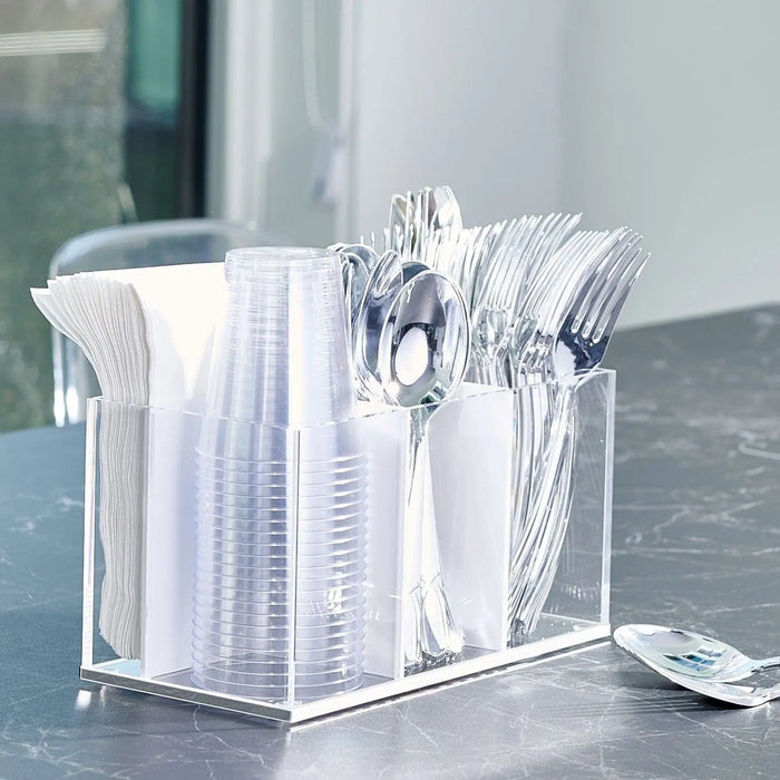 Clear acrylic silverware caddy holding white napkins, utensils, and napkin packets on a gray countertop, ideal for table service and entertaining.