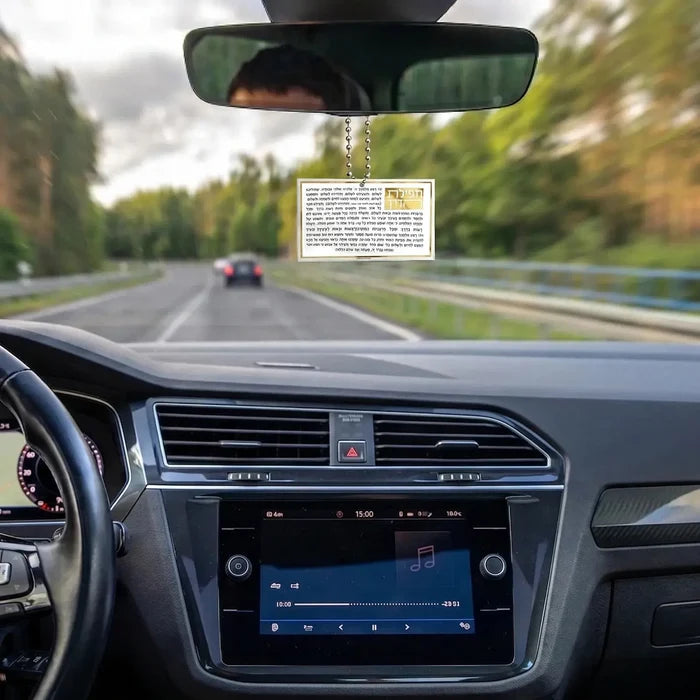 Classic Tefillas Haderech pocket-size keychain card displayed on car dashboard, white card with Hebrew text visible
