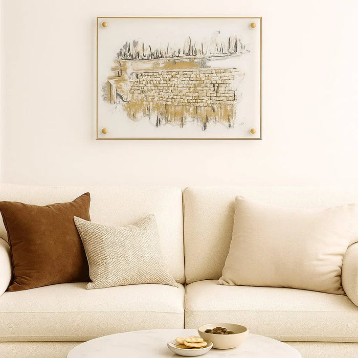 Clear Kosel at Winter painting by Waterdale Collection displayed above a cream sofa with gold accents, showing detailed Jerusalem artwork in warm tones.