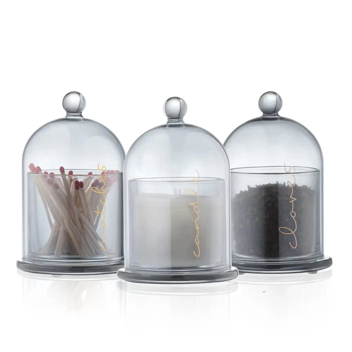 Three glass cloches with metal finials containing dried botanicals, spices, and grains for Cloche Havdalah Set by Waterdale Collection.