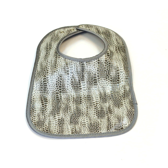 Crocodile patent leather bib in gray and cream textured pattern with snap closure, designed for babies and toddlers.