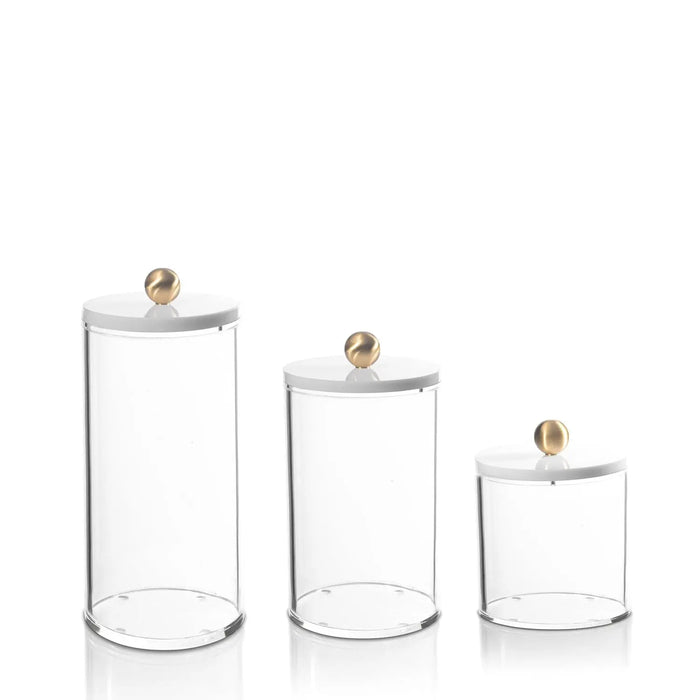 Three clear glass cylinder canisters with wooden lids in graduating sizes, ideal for kitchen storage and serveware organization.