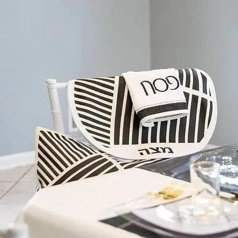 Diagonal Laser Cut Pesach Set in black and white striped leather with geometric patterns, displayed on a table setting.