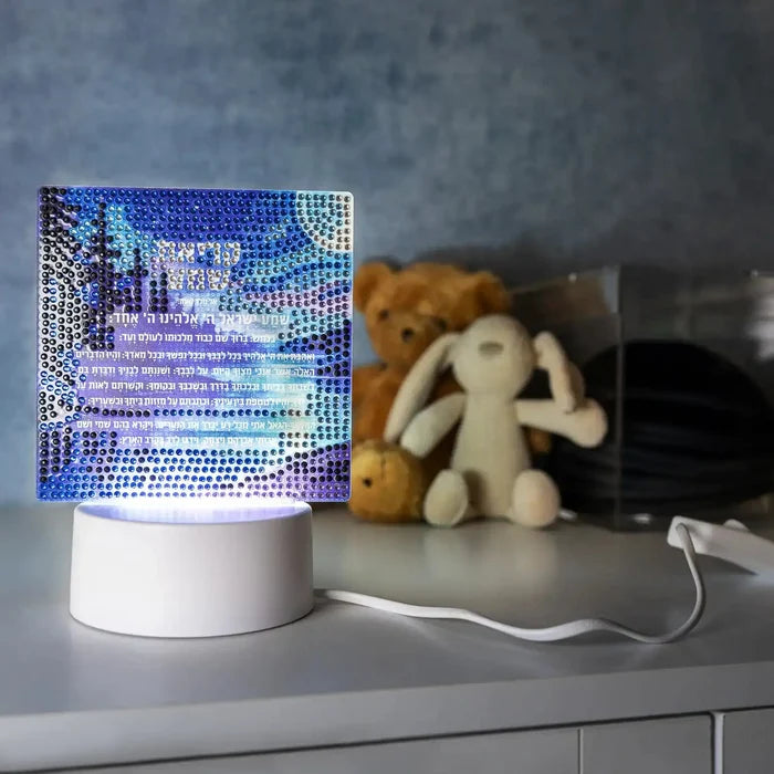 Diamond Art Kriyas Shema Lamp with blue and purple illuminated design on white base, displayed next to decorative items on shelf.
