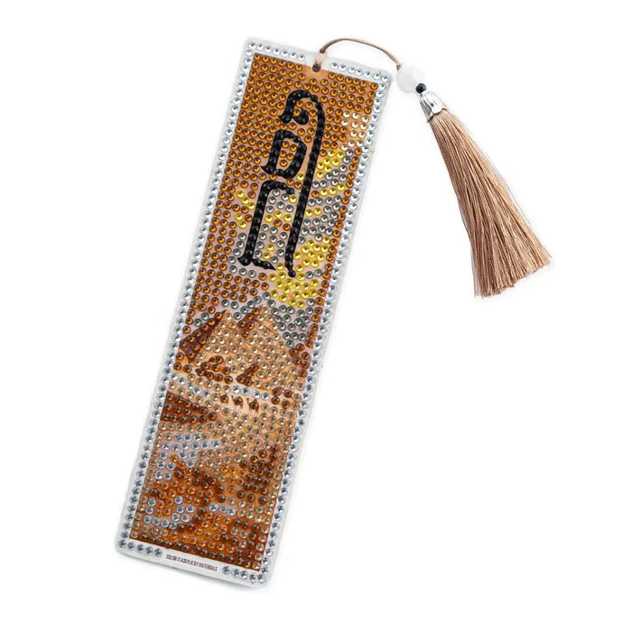 Diamond art pesach bookmark with orange, gold and brown color tones of diamond art on a leather bookmark with pesach words and designs on it. Gold tassel hanging from the top.
