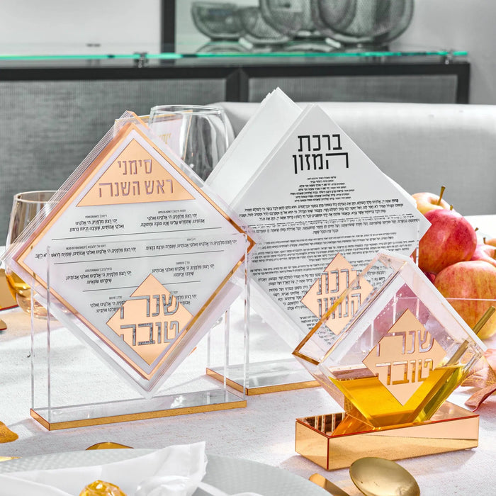 Diamond-shaped napkin holder and bencher set in rose gold and white by Waterdale Collection, displayed on marble surface with gold accents and gift wrapping.