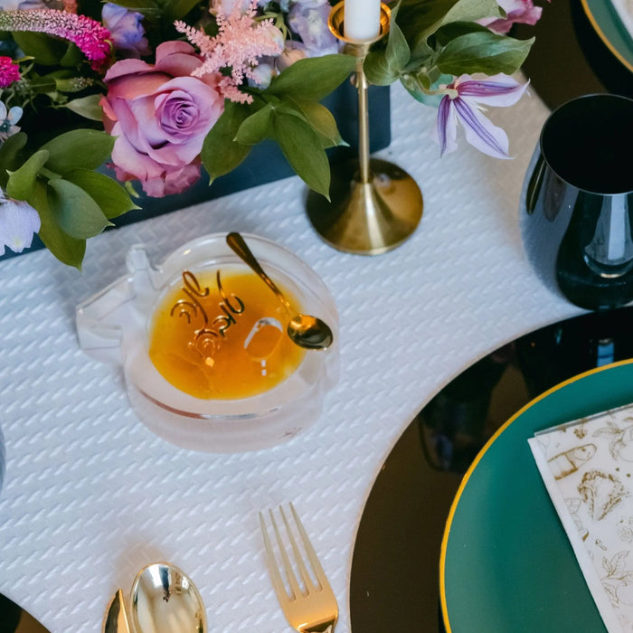 Gold die-cut apple honey dish on a Jewish New Year table setting