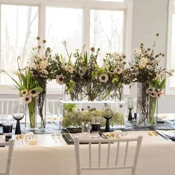 Clear glass Double Outline Vase by Waterdale Collection filled with white daisies and greenery in elegant table centerpiece display.