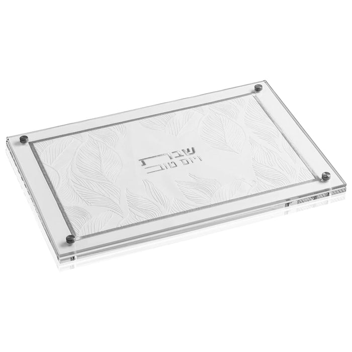 Clear acrylic challah board with embossed leaf design and silver metal corners, displayed from above angle.