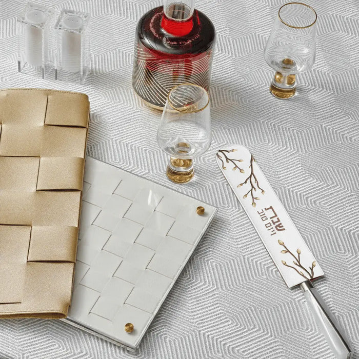 Embroidered leaf leather knife blade cover displayed with challah board and Shabbat items on white surface