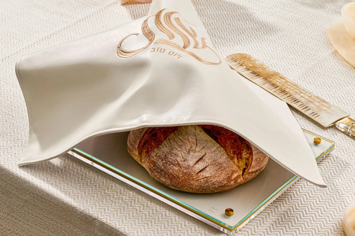 Embroidered Regal Challah Board in cream with gold accents, featuring a braided loaf on a white plate with cutlery on linen.
