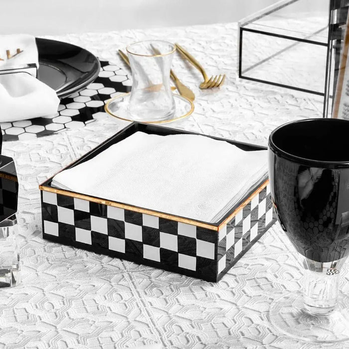 Filet crochet lace tablecloth in white displayed on marble surface with black checkered napkin holder and styling accessories.