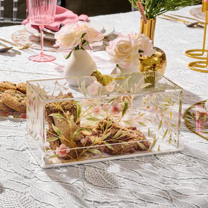 Clear glass floral bird cake dome with painted botanical design, displayed on table with gold accents and serveware for entertaining and holiday hosting.