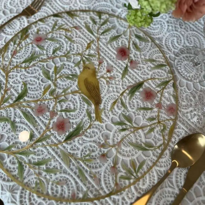 Floral bird charger with yellow songbird, delicate pink flowers, and green foliage on white lace background with gold rim.