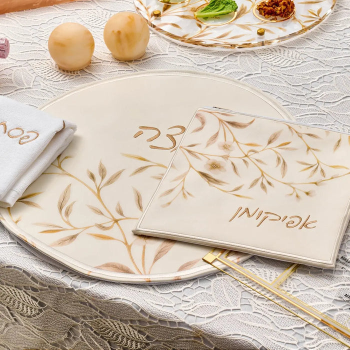 Waterdale Collection's Floral Bird Pesach set in gold and white leather, displayed on a table setting with place cards and tableware.