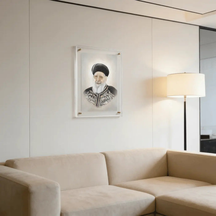 Framed portrait of R' Ovadia Yosef in light pearl marble frame displayed above a beige sofa in modern living room setting.