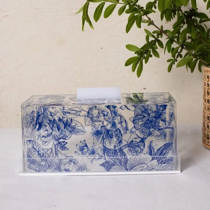French Toile Cake Dome with blue and white painted floral design, clear glass dome with decorative ceramic base, displayed with potted plant.