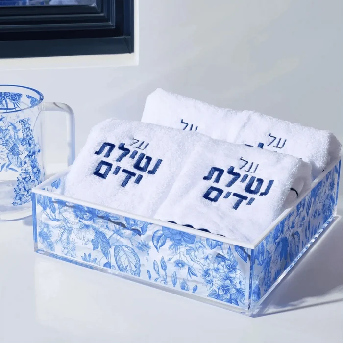 Blue and white decorative towel set with Hebrew text displayed in matching porcelain holder and pitcher