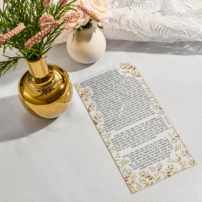 Frosted lucite Nishmas card with delicate floral bird design displayed on white surface next to gold vessel and greenery