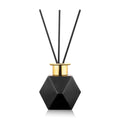 Black geometric hexagonal diffuser with gold trim and three reed sticks by Waterdale Collection