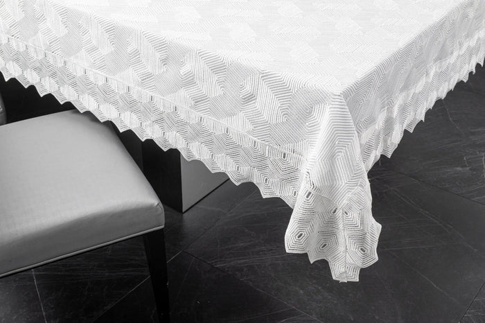 White geometric tablecloth with lace trim by Waterdale Collection, draped over table edge against dark background